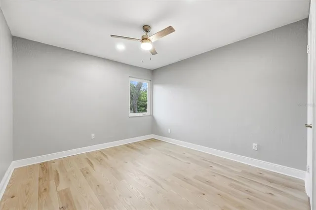 an empty room with a window and a ceiling fan