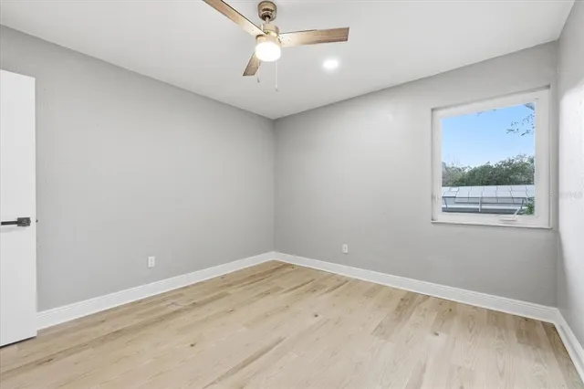 an empty room with a window and ceiling fan