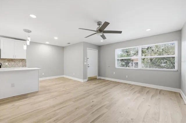 a view of an empty room with a window and wooden floor