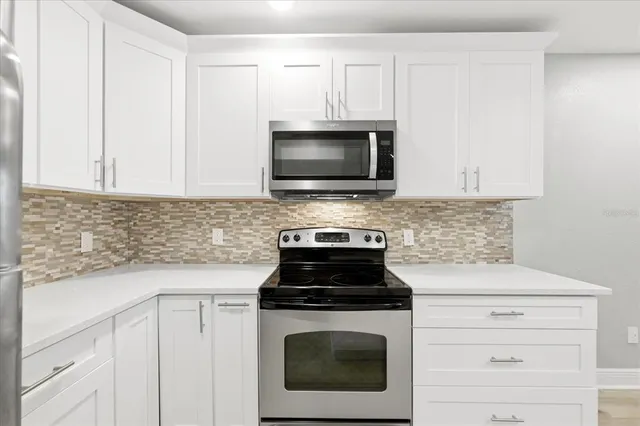 a kitchen with granite countertop white cabinets and black stove top oven with granite countertops