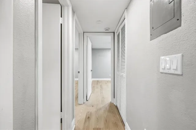 a view of a hallway with wooden floor and closet area