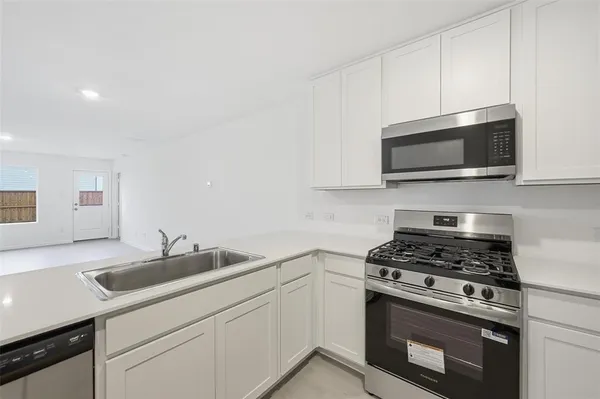 a kitchen with granite countertop a sink dishwasher stove and microwave with wooden floor