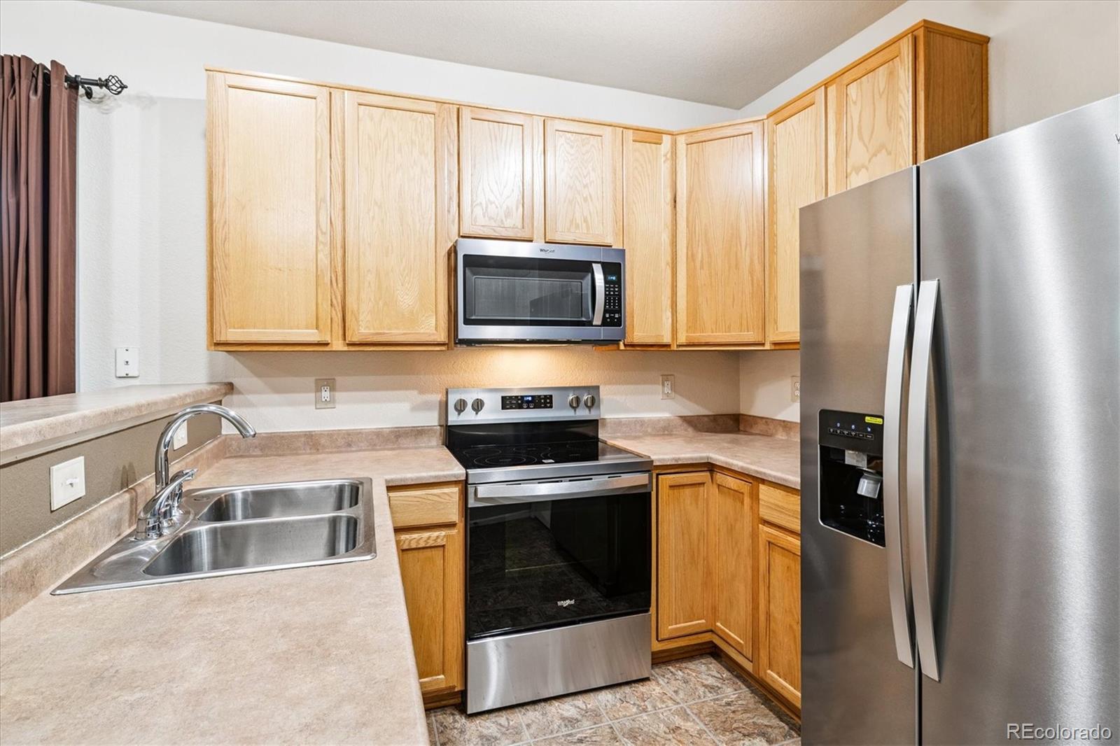 4658 Flower Street Wheat Ridge, CO 80033 - Photo 7 of 26 a kitchen with stainless steel appliances granite countertop a refrigerator stove and sink