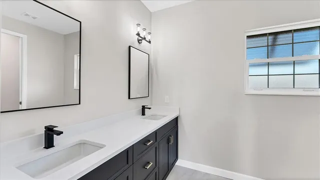 a bathroom with a double vanity sink a mirror and a shower