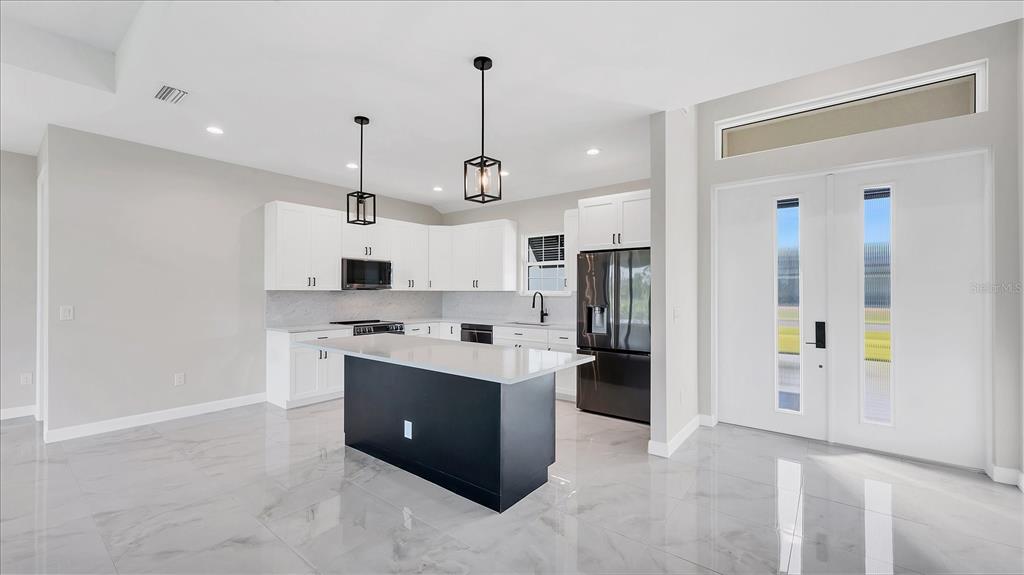 242 Brig Circle West Placida, FL 33946 - Photo 8 of 30 a kitchen with stainless steel appliances kitchen island granite countertop a refrigerator a stove oven and white cabinets with wooden floor