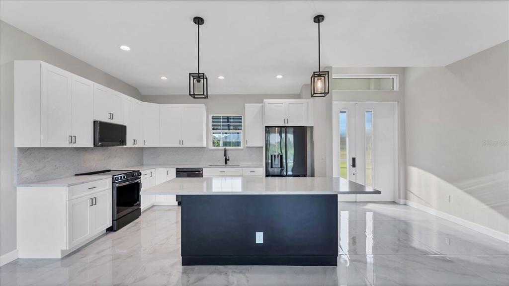 242 Brig Circle West Placida, FL 33946 - Photo 9 of 30 a kitchen with stainless steel appliances kitchen island granite countertop a refrigerator a stove a sink and white cabinets with wooden floor