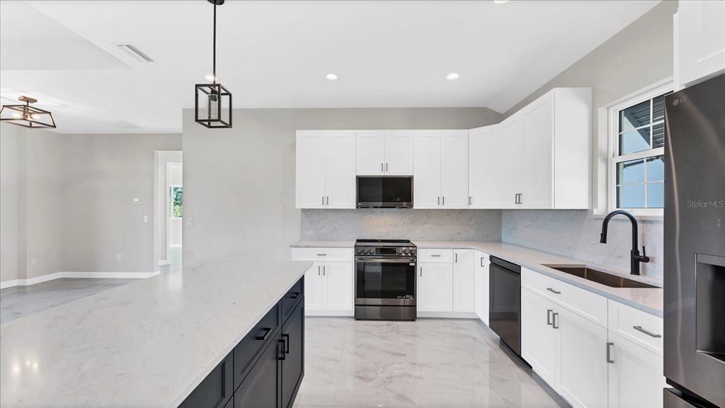 242 Brig Circle West Placida, FL 33946 - Photo 10 of 30 a kitchen with stainless steel appliances granite countertop a refrigerator a sink a stove and white cabinets