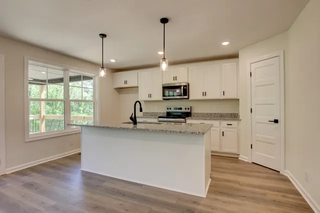 a kitchen with kitchen island white cabinets a sink a window and appliances