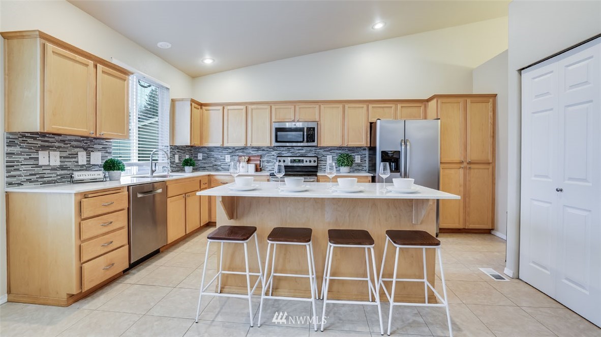 6725 Southeast 3rd Street Renton, WA 98059 - Photo 9 of 32 a large kitchen with kitchen island granite countertop a stove a sink a dining table and chairs