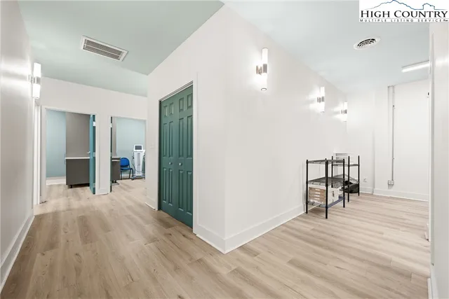 a view of a hallway with wooden floor table and chairs