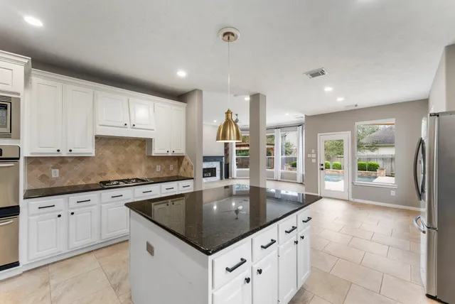 a kitchen with granite countertop a sink a counter top space stainless steel appliances and cabinets