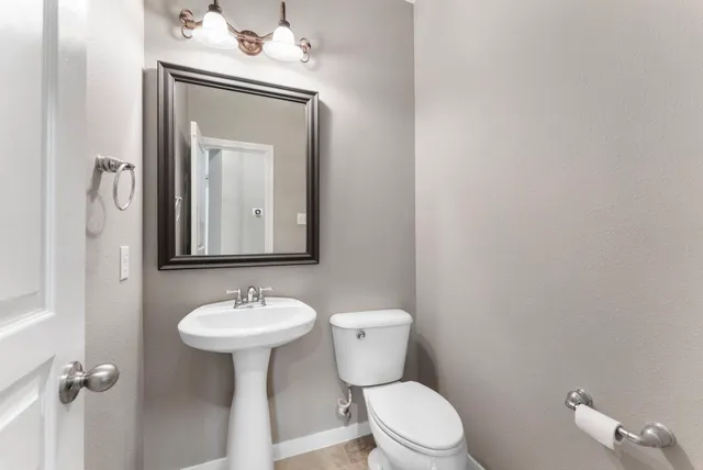 a bathroom with a toilet sink vanity and mirror