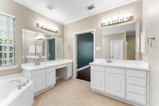 a spacious bathroom with a double vanity sink mirror and bathtub