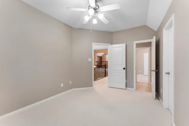 an empty room with chandelier fan and closet area