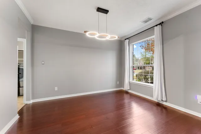 an empty room with wooden floor exposed radiator and windows