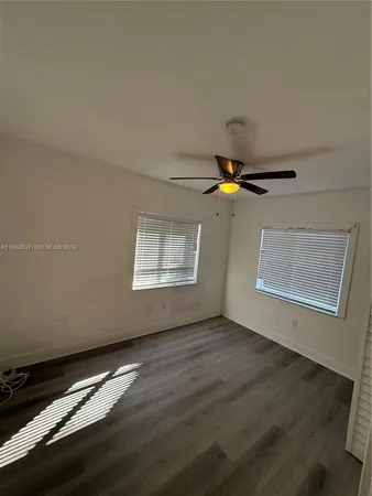 a view of an empty room with window and wooden floor
