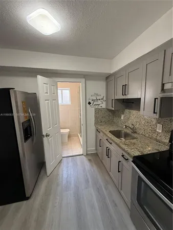 a large kitchen with a stove a sink dishwasher a refrigerator and wooden floor