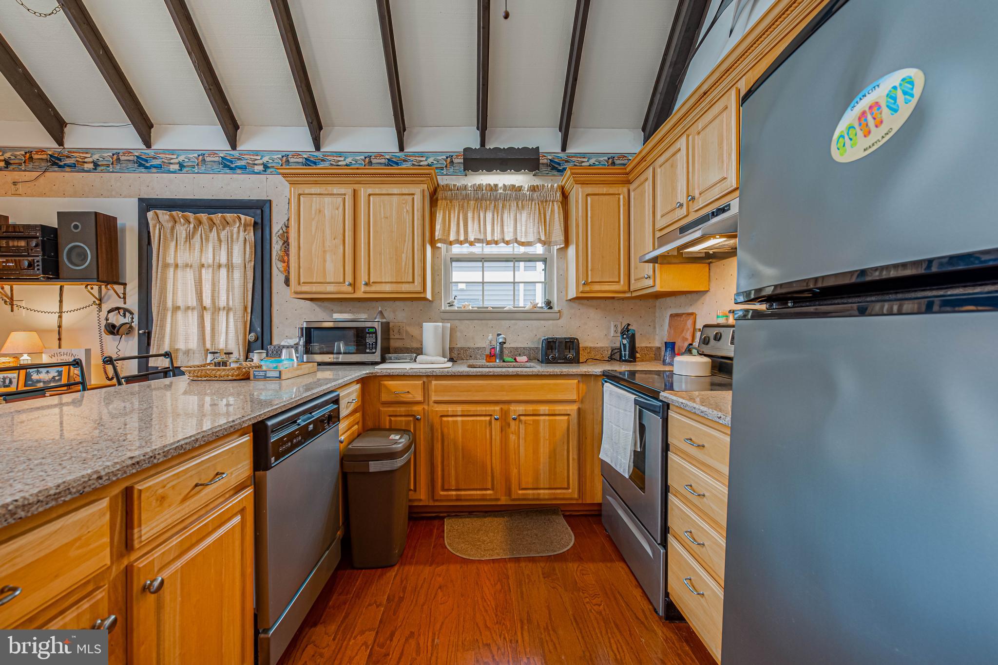 10602 Pine Needle Road Ocean City, MD 21842 - Photo 13 of 36 a kitchen with stainless steel appliances granite countertop a refrigerator a sink dishwasher a stove and white countertops with wooden floor