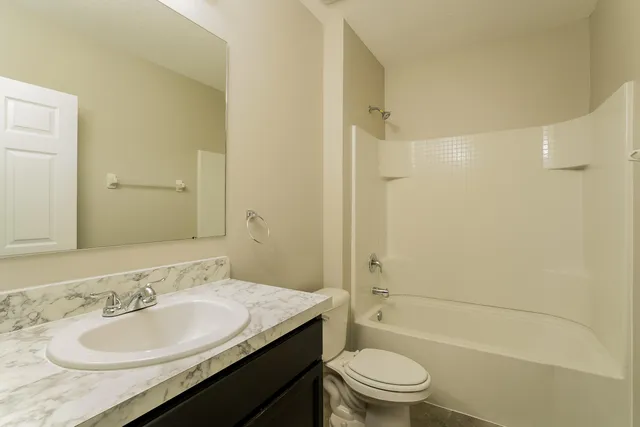 a bathroom with a granite countertop sink a toilet and shower