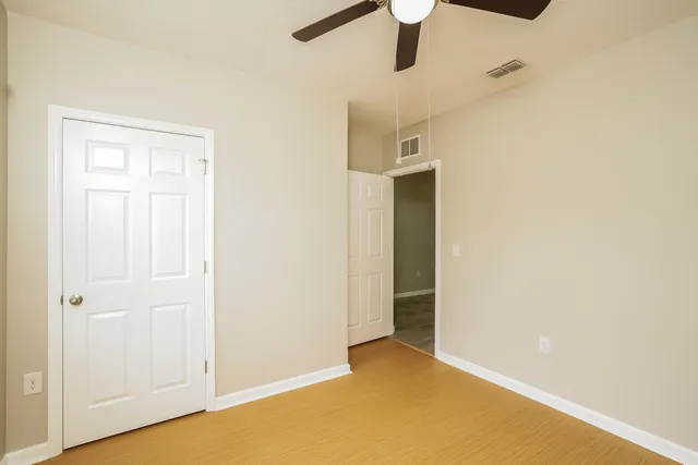 an empty room with a ceiling fan and wooden floor