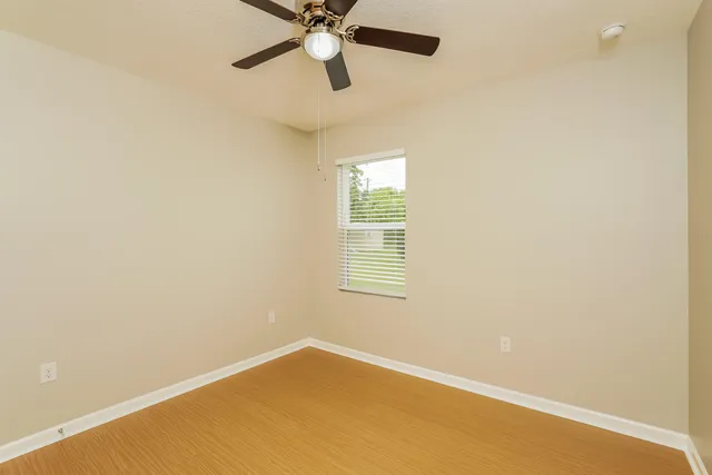 an empty room with a window and a fan