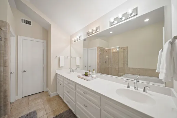 a spacious bathroom with a double vanity sink a large mirror and a shower