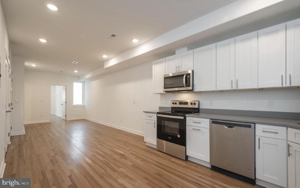727 North 39th Street, Unit 2 Philadelphia, PA 19104 - Photo 7 of 15 a kitchen with stainless steel appliances granite countertop a stove top oven a sink dishwasher and a microwave oven with wooden floor
