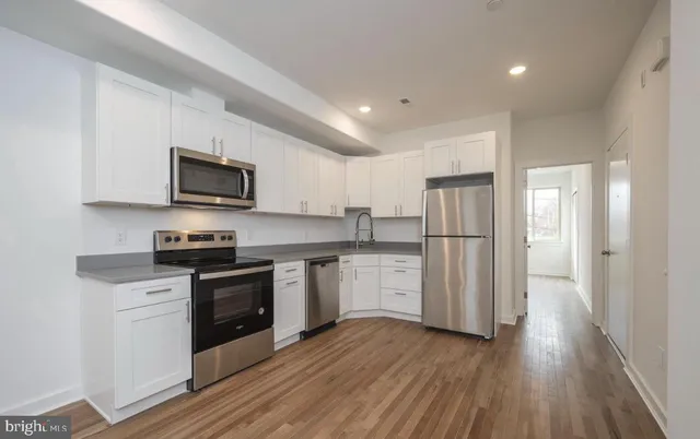 a kitchen with stainless steel appliances granite countertop a refrigerator a stove top oven a sink dishwasher and wooden floor