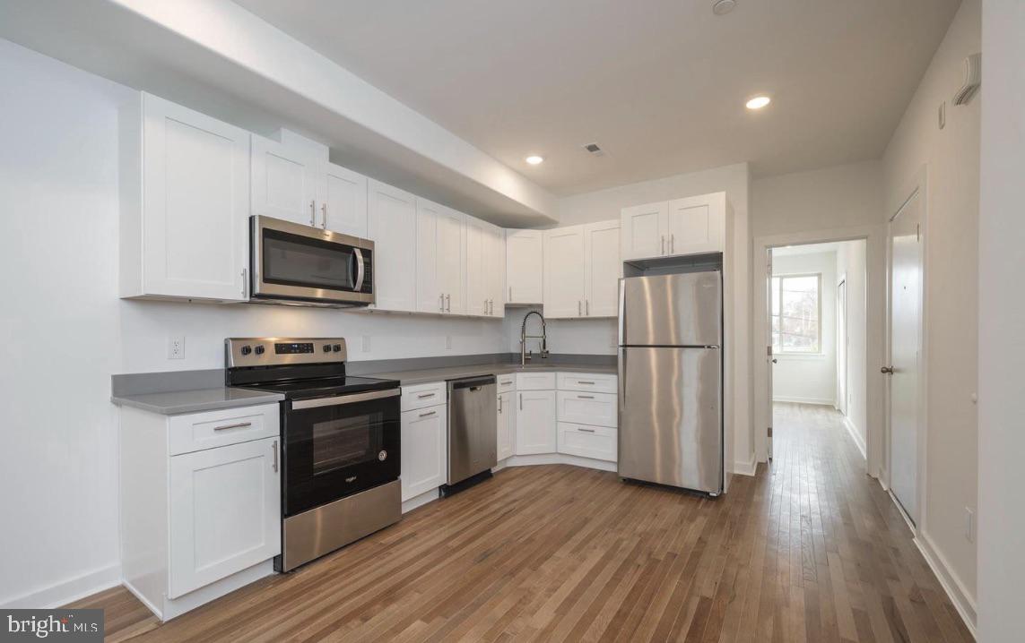 727 North 39th Street, Unit 2 Philadelphia, PA 19104 - Photo 8 of 15 a kitchen with stainless steel appliances granite countertop a refrigerator a stove top oven a sink and dishwasher with wooden floor
