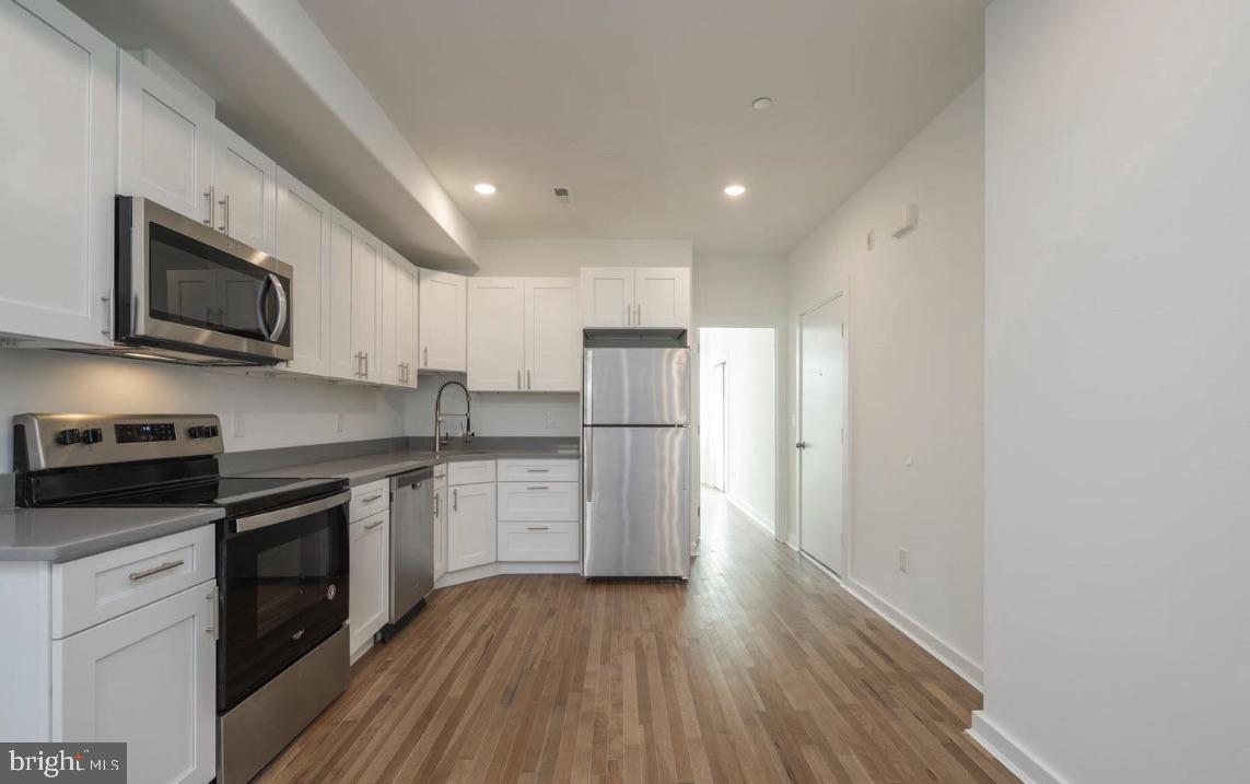 727 North 39th Street, Unit 2 Philadelphia, PA 19104 - Photo 9 of 15 a kitchen with stainless steel appliances granite countertop a refrigerator a stove top oven a sink dishwasher and wooden floor
