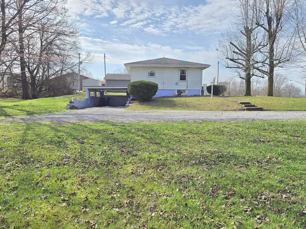 a front view of house with yard and trees in the background