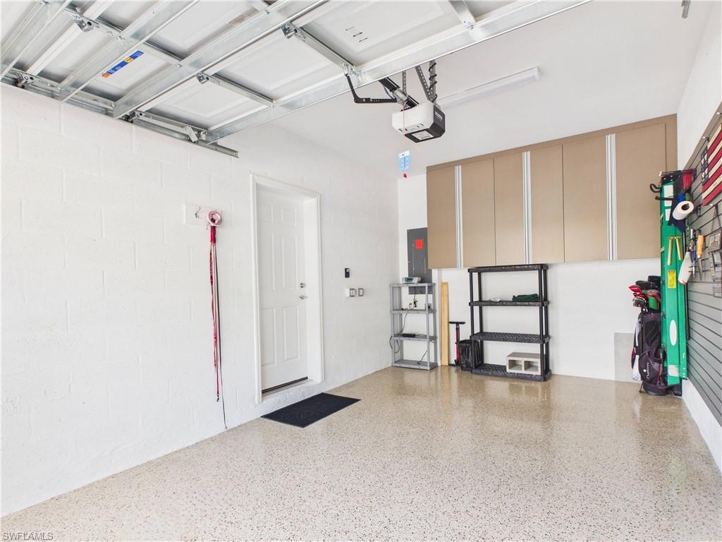 5683 Mayflower Way, Unit 908 Ave Maria, FL 34142 - Photo 34 of 37 Garage with concrete block wall, electric panel, and a garage door opener