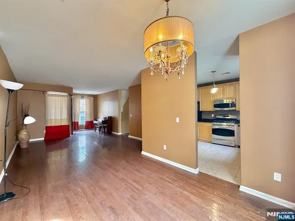 a view of a livingroom with furniture wooden floor kitchen chandelier and a refrigerator