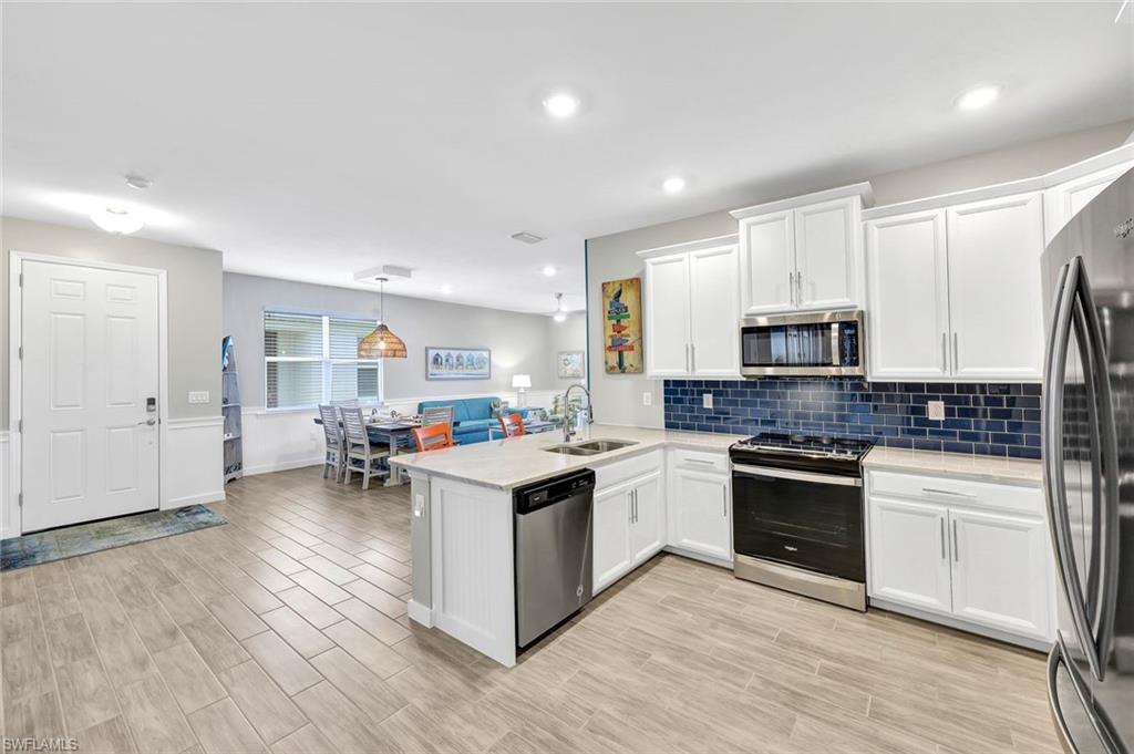 1261 Enbrook Loop Naples, FL 34114 - Photo 6 of 23 a kitchen with stainless steel appliances granite countertop a stove top oven a sink dishwasher and a refrigerator with wooden floor