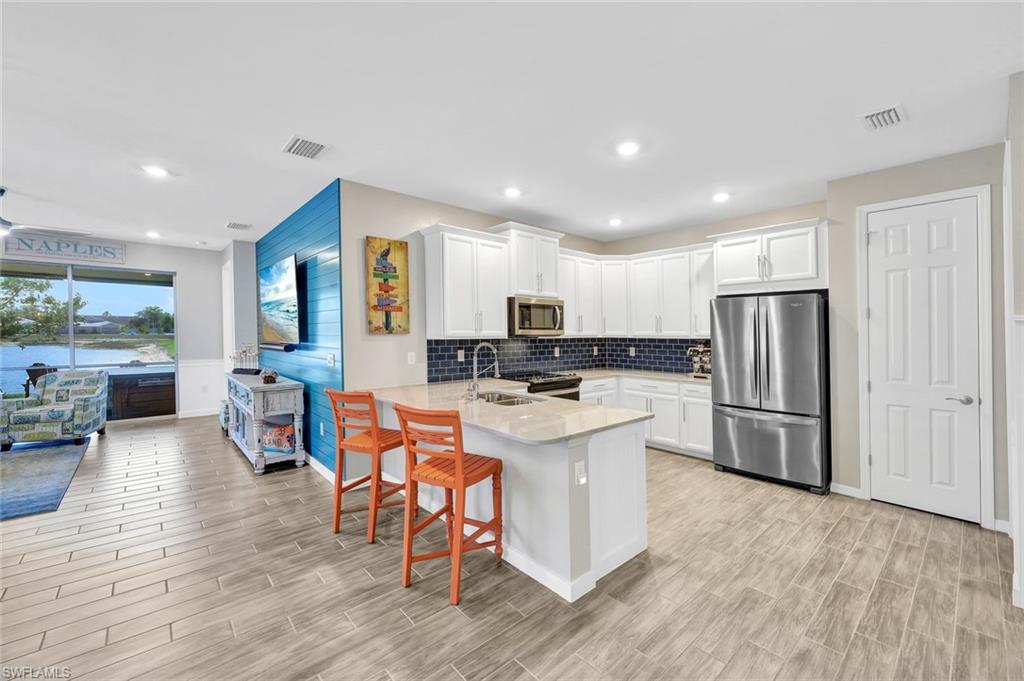 1261 Enbrook Loop Naples, FL 34114 - Photo 7 of 23 a kitchen with stainless steel appliances a refrigerator a stove a sink dishwasher with a dining table and chairs with wooden floor