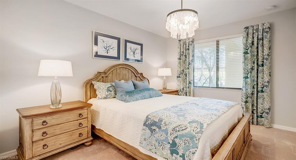 9584 Trevi Court, Unit 5227 Naples, FL 34113 - Photo 15 of 26 a bedroom with a bed and a chandelier