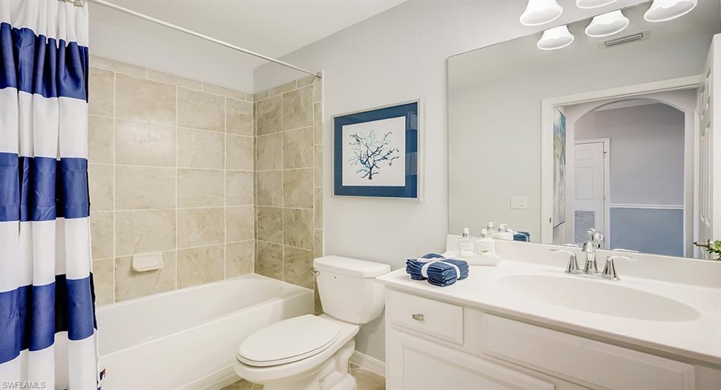 9584 Trevi Court, Unit 5227 Naples, FL 34113 - Photo 16 of 26 a bathroom with a sink a toilet a mirror a vanity a bath tub and shower