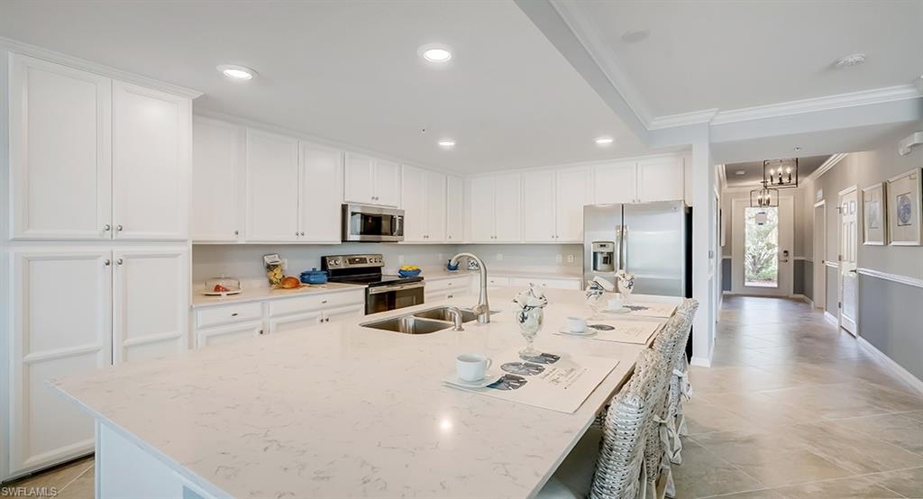 9584 Trevi Court, Unit 5227 Naples, FL 34113 - Photo 6 of 26 a kitchen with stainless steel appliances granite countertop a sink a stove a refrigerator a center island and white cabinets