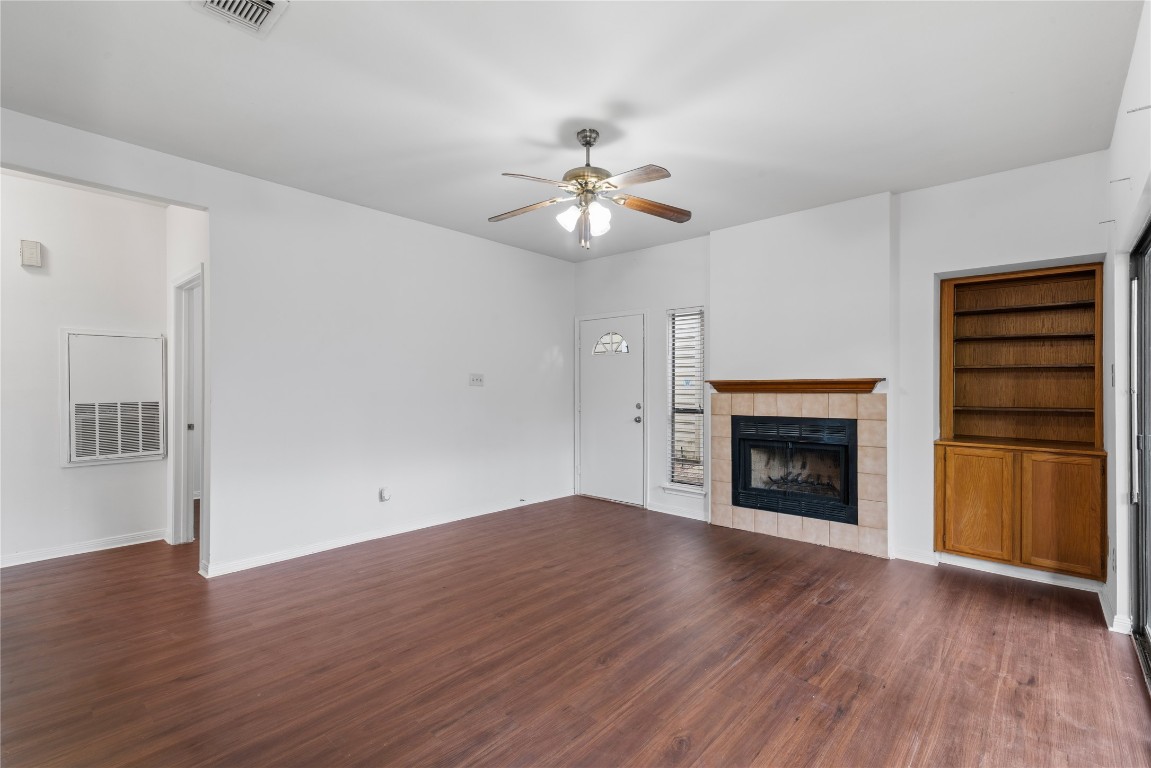 3500 Tangle Brush Drive, Unit 193 Spring, TX 77381 - Photo 12 of 26 Spacious living room features wood flooring, a cozy fireplace with a tile surround, and built-in shelving. It has a ceiling fan for comfort and natural light from the adjacent window.