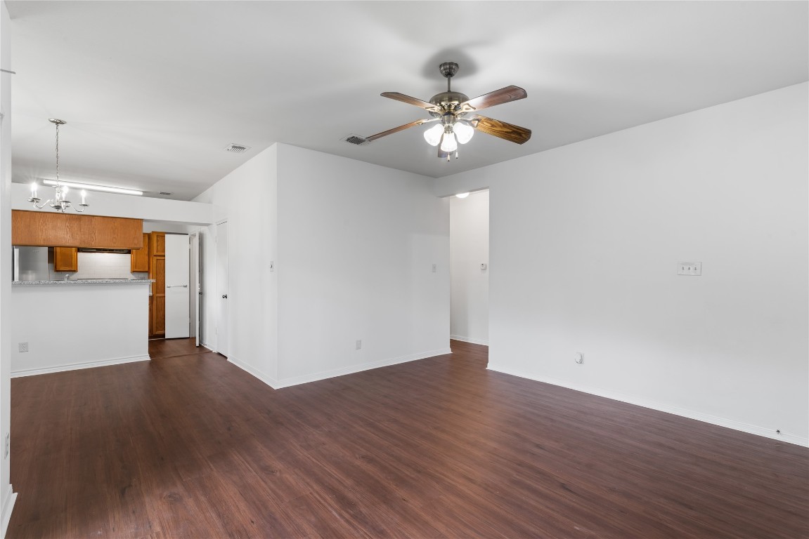 3500 Tangle Brush Drive, Unit 193 Spring, TX 77381 - Photo 13 of 26 Spacious, open-concept living and dining area with hardwood flooring, a ceiling fan, and white walls. The kitchen features wooden cabinets and a breakfast bar, enhancing the home's modern feel.