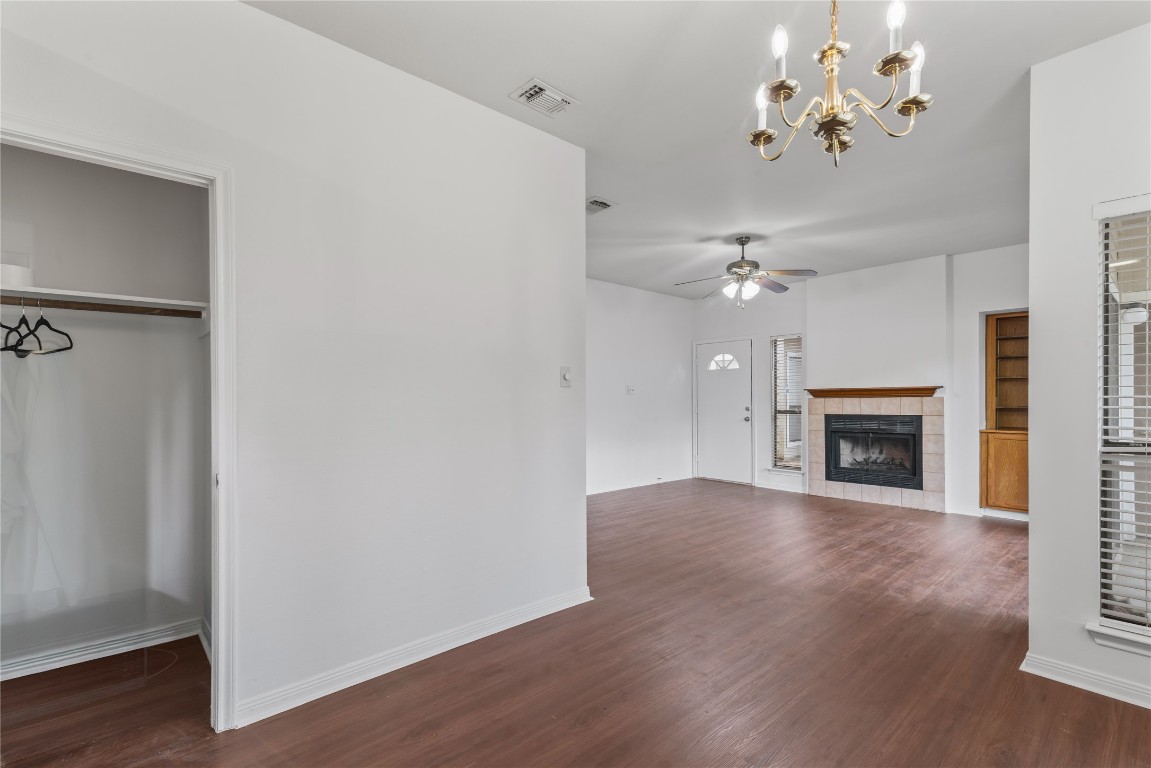 3500 Tangle Brush Drive, Unit 193 Spring, TX 77381 - Photo 25 of 26 This photo showcases a bright, open living space with hardwood floors, a ceiling fan, and a cozy fireplace. The area features a built-in shelf and chandelier, adding charm and functionality. A closet is visible, providing storage convenience.