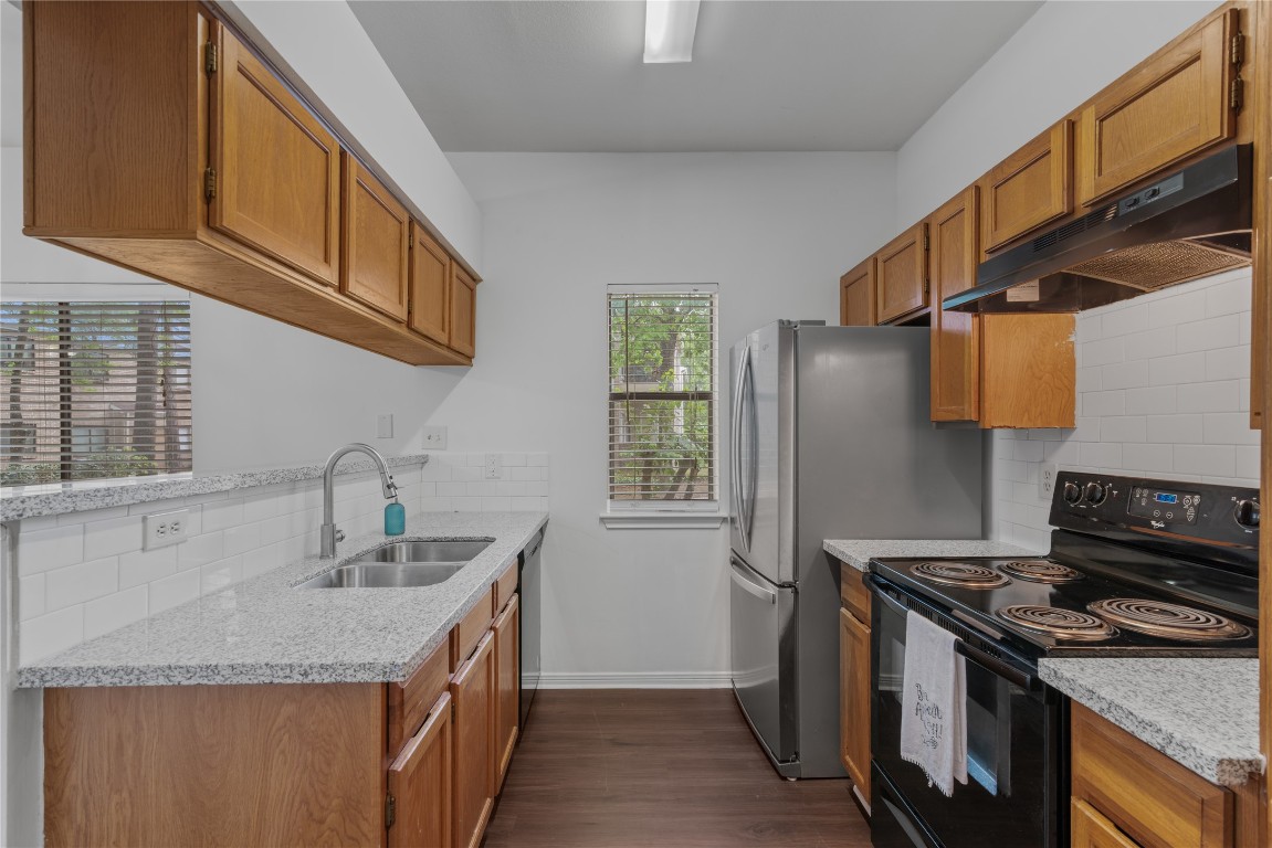 3500 Tangle Brush Drive, Unit 193 Spring, TX 77381 - Photo 6 of 26 Sleek granite countertops, warm wooden cabinets, and modern stainless steel appliances. It has a cozy layout with a window offering natural light and a view of greenery.
