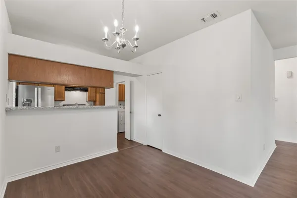 a view of an empty room with wooden floor and a ceiling fan