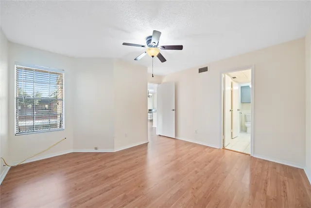 an empty room with wooden floor ceiling fan and windows
