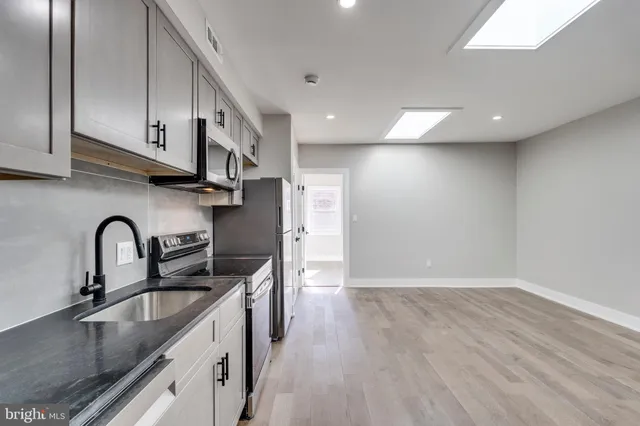 a kitchen with stainless steel appliances granite countertop a sink a stove and a refrigerator