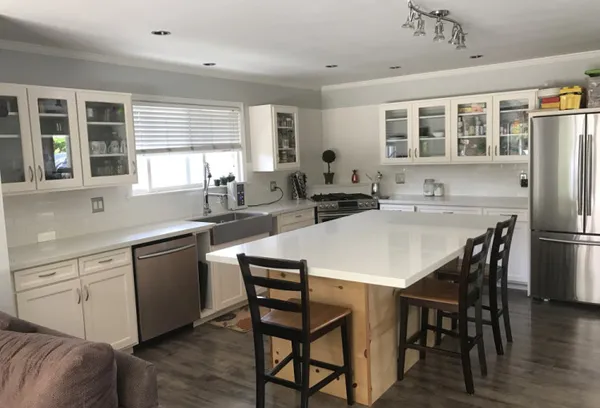 a kitchen with stainless steel appliances granite countertop a dining table chairs refrigerator sink and cabinets