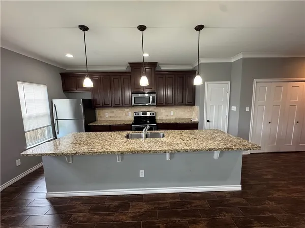 a view of dining room with granite countertop kitchen island stainless steel appliances sink and wooden floor