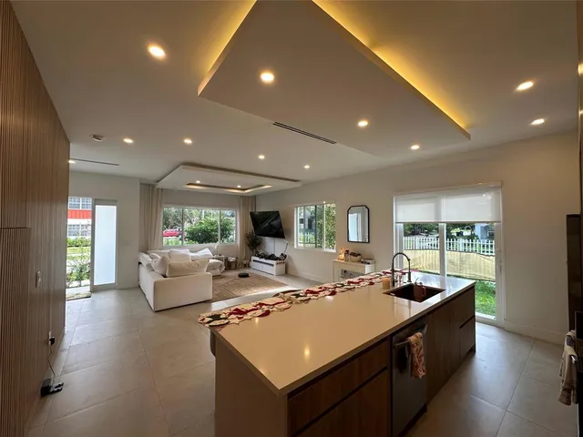 a large living room with stainless steel appliances granite countertop couches a flat screen tv