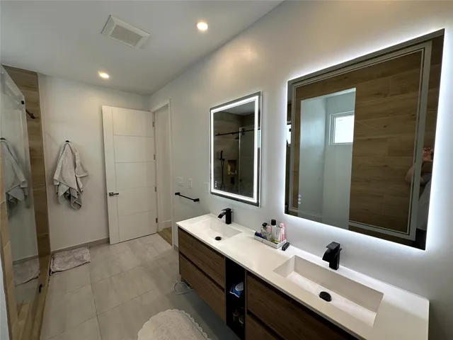 a bathroom with a double vanity sink mirror and shower