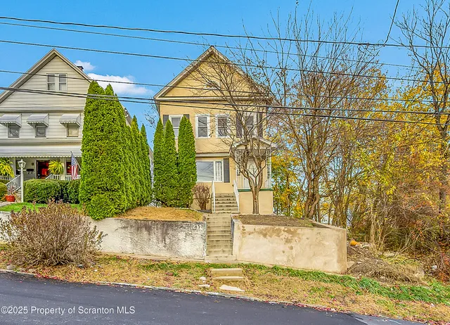 a view of a house with large windows and a small yard